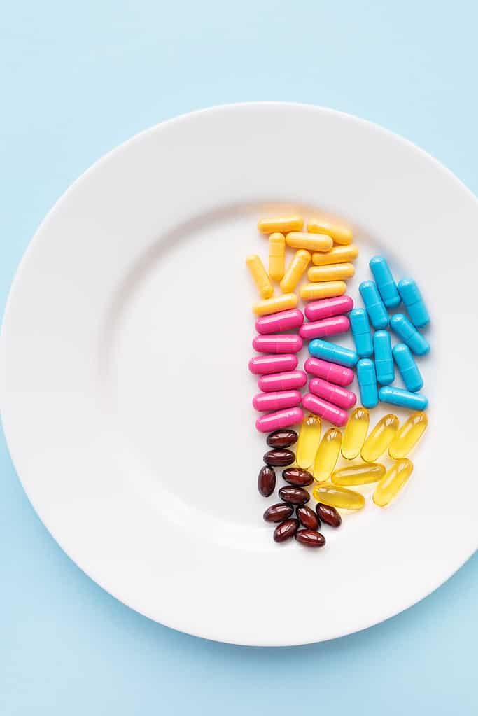 Food supplements-capsules of bright color lie on a white plate in a heap. Concept of medicine and