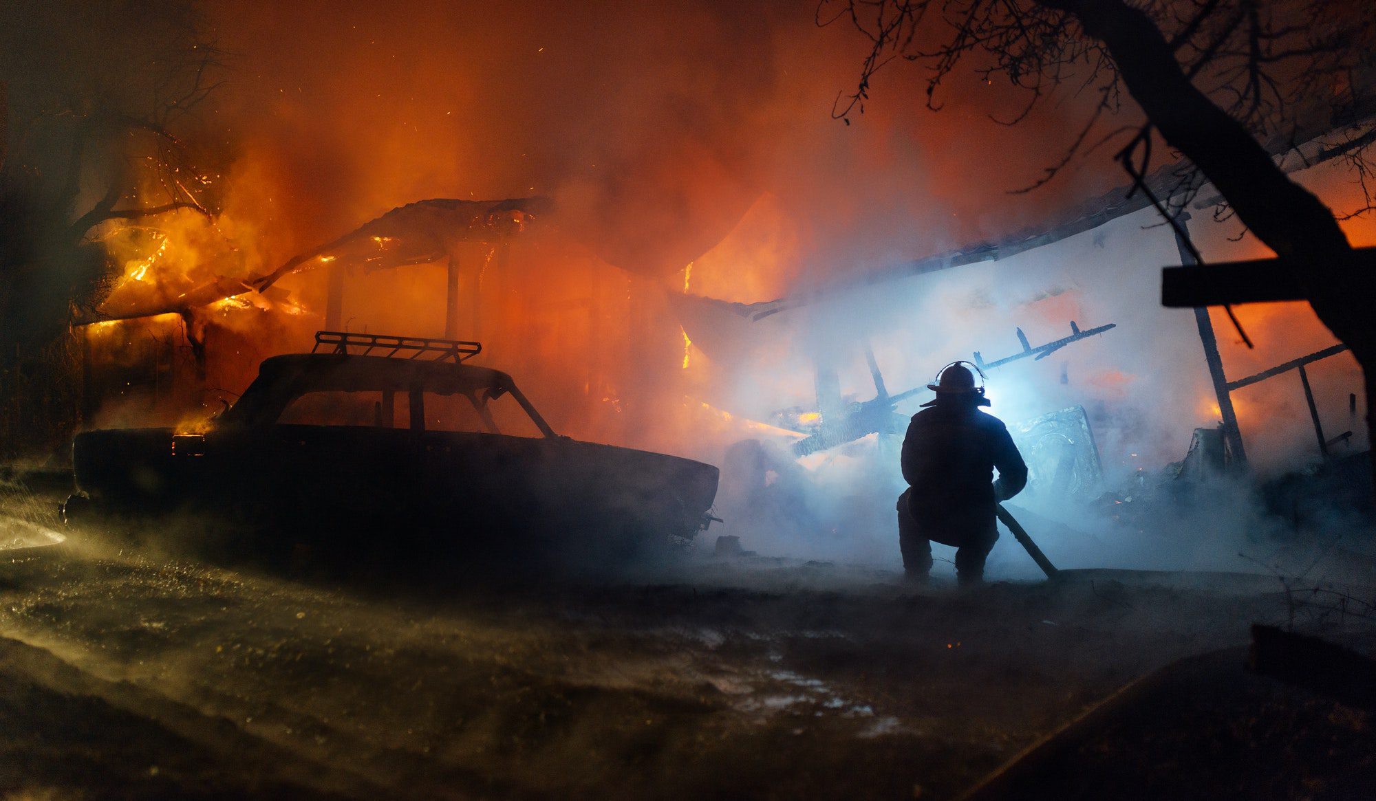 Firefighter putting out the fire of the house and car